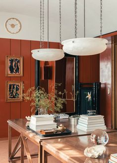 a dining room table with books on it and two lights hanging from the ceiling above