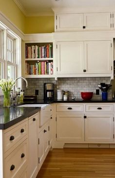 a kitchen filled with lots of white cabinets and black counter tops next to a window