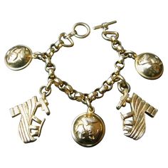 Salvatore Ferragamo Gilt metal shoe themed charm bracelet c 1990s The stylish bracelet is adorned with a collection of large scale dangling charms Two of the gilt metal charms are a pair of platform shoes which is a recurring theme in Ferragamo designs The remaining three circular dome-shaped charms are designed with a trio of shoe designs Makes a chic timeless accessory All five charms are inscribed: Ferragamo Measurements: The length secures at 8 inches exclusively Secures with a toggle style Shoe Designs, Modern Bracelets, Vintage Charm Bracelet, Metal Charms, Stylish Bracelet, Locket Charms, Timeless Accessories, Shoe Charms, Metal Charm