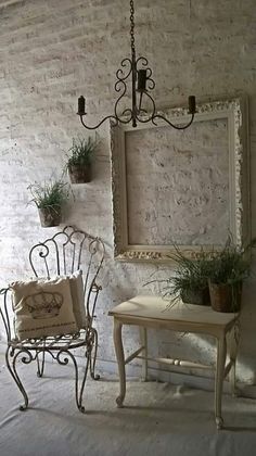 two chairs and a table in front of a brick wall with potted plants on it