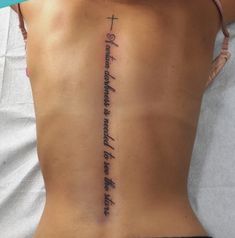 the back of a woman with a cross tattoo on her lower back