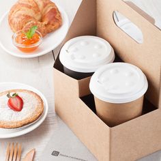 there are three cups in the box with strawberries on it and a croissant