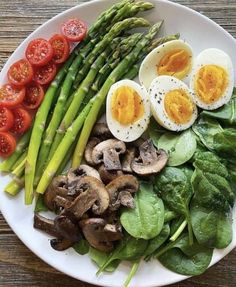 a white plate topped with asparagus, hard boiled eggs and mushrooms