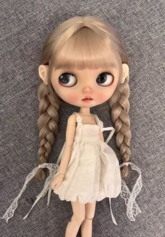 a doll with long blonde hair wearing a white dress and braids on her head