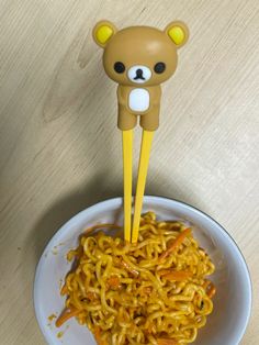 a bowl with noodles and a teddy bear sticking out of it