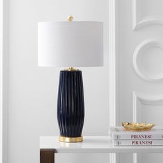 a table with a lamp, books and a book on top of it in front of a white door