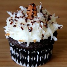 a cupcake with white frosting and chocolate sprinkles, topped with coconut