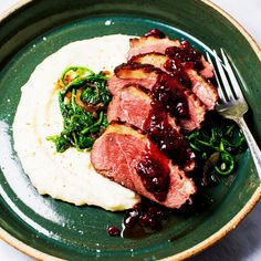 a green plate topped with meat and veggies on top of mashed potatoes