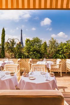 an outdoor dining area with tables, chairs and umbrellas on the deck overlooking the eiffel tower