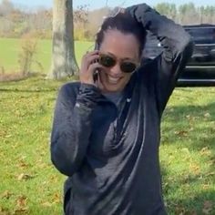 a woman is talking on her cell phone in front of a car and holding it up to her head