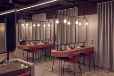 an empty restaurant with red chairs and lights hanging from the ceiling, along with curtains