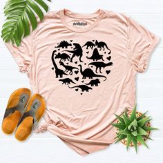 a t - shirt with dinosaurs in the shape of a heart on top of a table