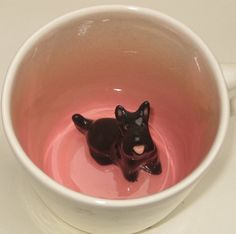 a small black dog sitting in a coffee cup