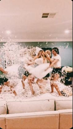 a group of people standing on top of a couch in front of a wall covered in confetti