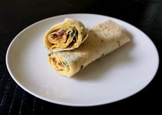 a burrito on a white plate sitting on a table