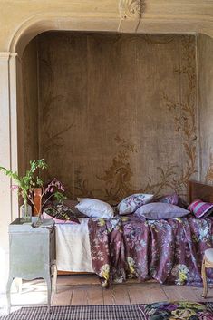 a bed sitting in the middle of a room next to a table with flowers on it