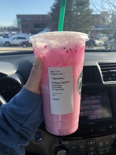 a person holding up a pink drink in their hand