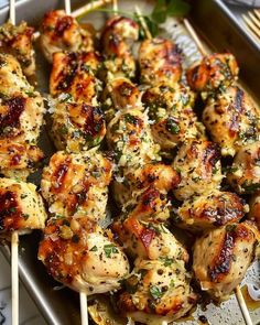 chicken skewers with sauce and herbs on a tray