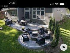 an outdoor patio with chairs and fire pit in the middle, surrounded by green grass