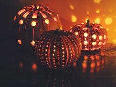 three lit pumpkins sitting on top of a table next to each other with holes in them