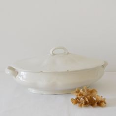 a white dish with some food on it next to the bowl and spoon that has been used as a garnisher