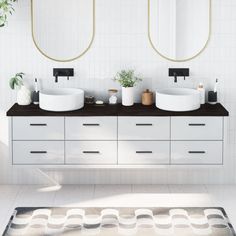 a bathroom with two sinks and mirrors on the wall next to a rug in front of it