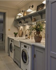 a washer and dryer in a room with open shelving on the wall