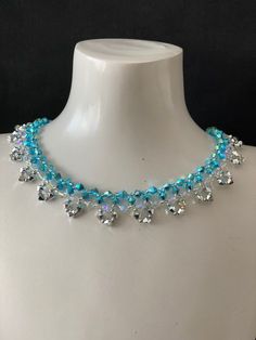 a white mannequin with blue and clear beads on it's neckline