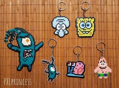 four pixel keychains are sitting on a bamboo mat, each with different characters