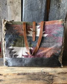 a multicolored tote bag sitting on top of a wooden table next to a wall