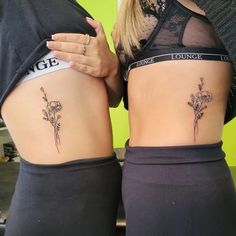 two women with tattoos on their stomachs, one has a flower and the other has a name