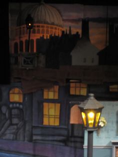 a street light sitting in front of a painting on the side of a building at night