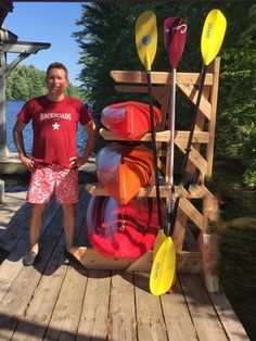 a man standing on a dock with kayaks and paddles attached to the rack