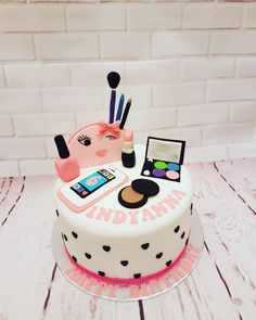 there is a cake with makeup and cosmetics on the top, along with other items