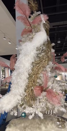 a white christmas tree with pink and gold feathers