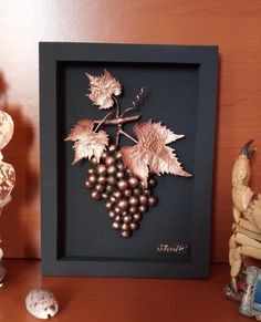 there are some figurines on the shelf next to a frame with grapes and leaves