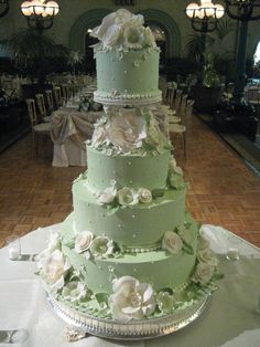 a three tiered green wedding cake sitting on top of a table in a banquet hall