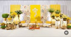 a decorated stage with yellow and white flowers in vases on the floor next to chairs