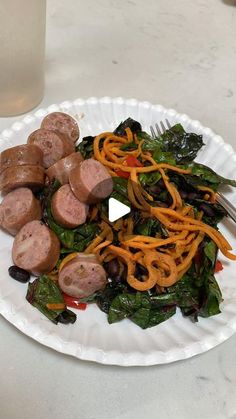 a white plate topped with meat and veggies next to a glass of water