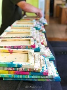 a man standing next to a long table covered in different types of paintbrushes