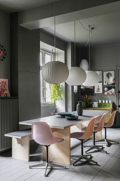 a dining room table with four chairs around it and hanging lights on the wall above