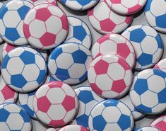 a pile of soccer balls with pink and blue designs on the top one is white