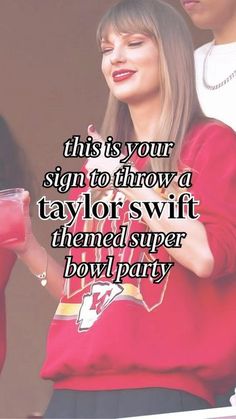 a woman in a red sweatshirt is holding a drink and looking at her cell phone with the caption, this is your sign to throw a taylorswit themed super bowl party