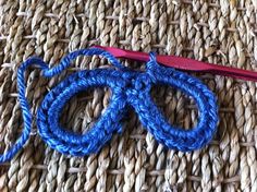 a pair of scissors sitting on top of a piece of blue yarn next to an orange crochet hook