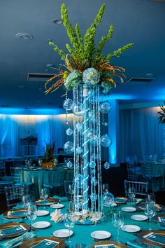 a tall vase filled with lots of flowers on top of a blue table cloth covered table