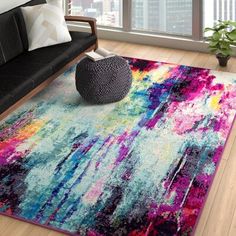 a living room with a black couch and colorful rug