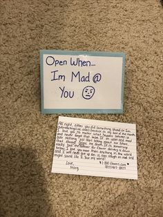 a note and pen sitting on the floor next to a sign that says open when i'm mad at you