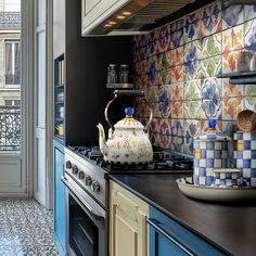 a tea kettle sitting on top of a stove next to a wall covered in tiles