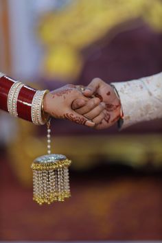 the bride and groom are holding hands with their wedding rings hanging from each other's fingers