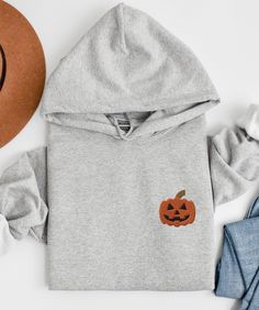 CHRISTMAS DEADLINE: We can no longer guarantee shipment by Christmas. Sorry :(  This cozy unisex hoodie is embroidered with a jack-o-lantern :)  * 50% pre-shrunk cotton, 50% polyester * Fabric weight: 8.0 oz/yd² (271.25 g/m²) * Air-jet spun yarn with a soft feel and reduced pilling * Double-lined hood with matching drawcord * Quarter-turned body to avoid crease down the middle * 1 × 1 athletic rib-knit cuffs and waistband with spandex * Front pouch pocket * Double-needle stitched collar, shoulde Halloween Long Sleeve Sweatshirt With Drawstring Hood, Hooded Embroidered Sweatshirt For Halloween, Halloween Embroidered Crew Neck Hoodie, Halloween Cotton Sweatshirt With Drawstring Hood, Embroidered Long Sleeve Hoodie For Fall, Hoodie Embroidery, Embroidered Halloween, Stitch Hoodie, Embroidery Hoodie